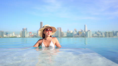 Young-Young-in-hat-relaxing-in-swimming-pool-on-the-rooftop-of-hotel-and-enjoy-Bangkok-cityscape