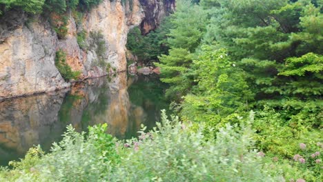 4k drone video of beautiful mountain pond surrounded by trees at emerald village near little switzerland, nc on summer day-1