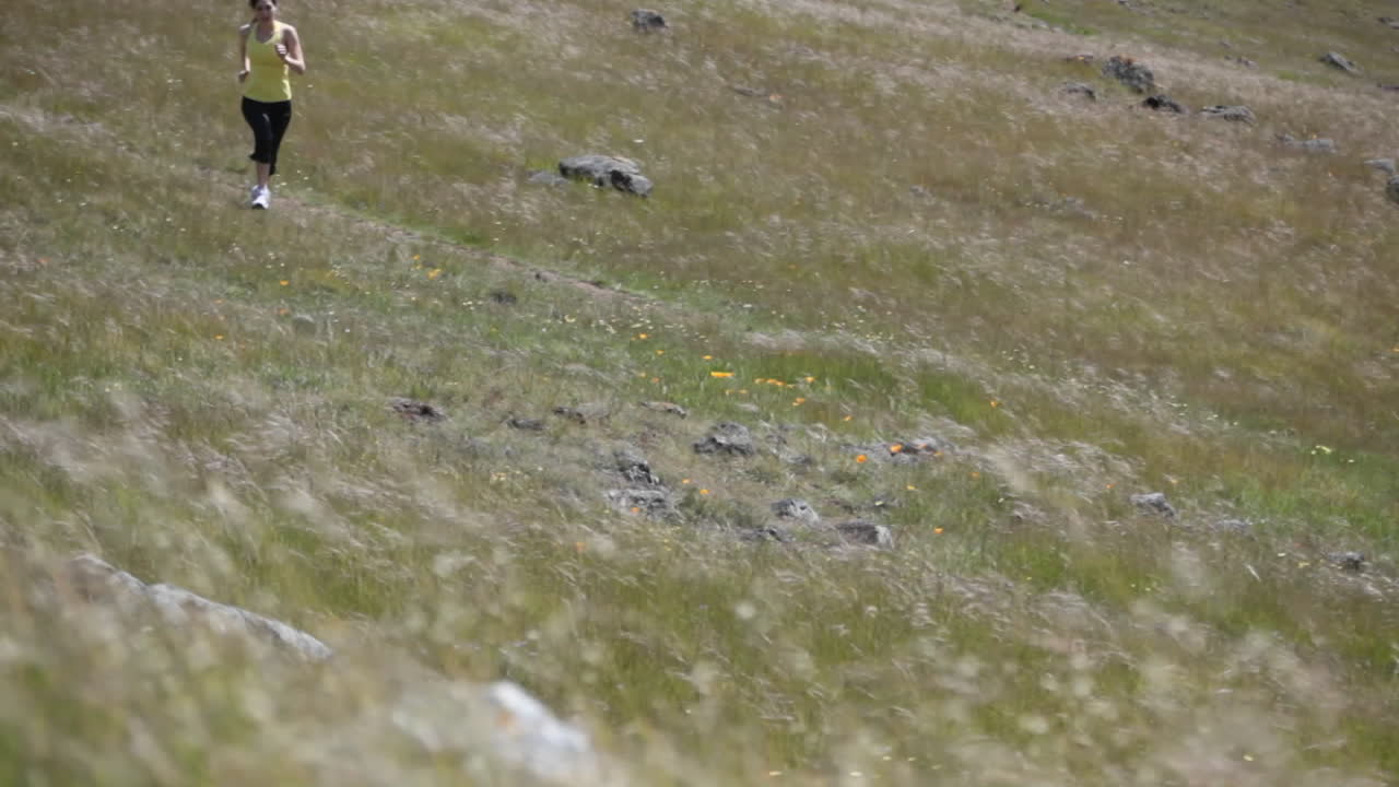 한 여자가 언덕의 거친 지형을 조깅한다
