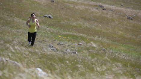 a woman jogs up the rough terrain of a hill