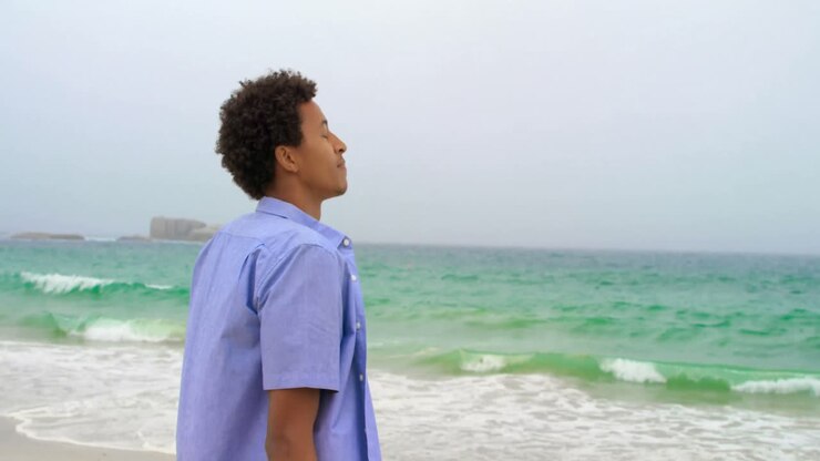 Vista laterale di uomo afroamericano in piedi sulla spiaggia 4k