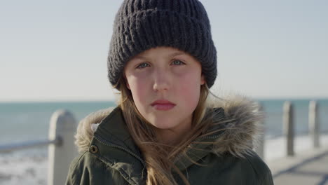 portrait cute little cacuasian girl looking serious wearing warm clothes beanie on seaside beach contemplative child slow motion