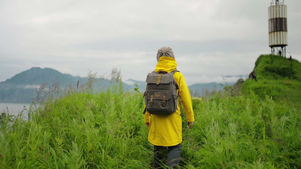 Woman Hiking in Mountains with Yellow Raincoat