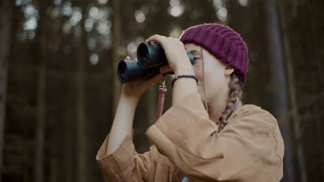 female tourist looking through binoculars in forest