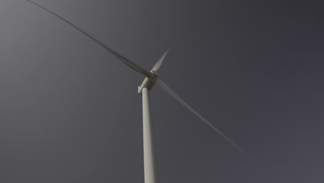 wind turbine from bellow and in front, head spinning with blue sky background