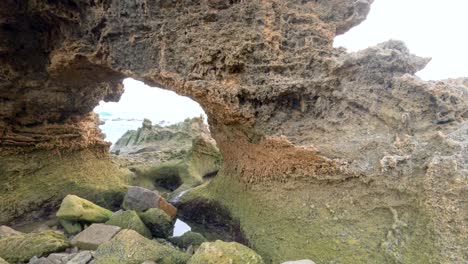 a detailed view of rugged coastal rock formations with natural arches and tidal pools under soft daylight
