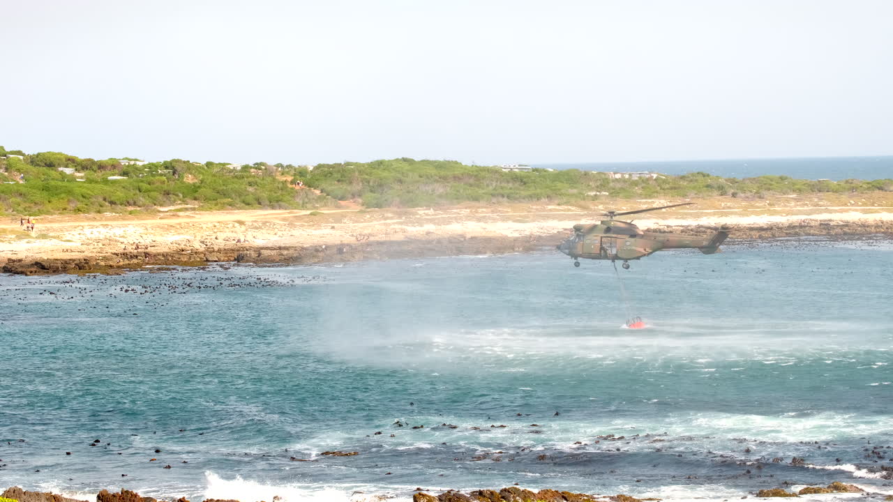 Aerial firefighting army helicopter scoop seawater to water-bomb wildfire