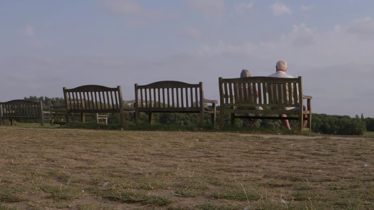 공원 와이드 샷의 벤치에서 전망을 즐기는 은퇴한 커플