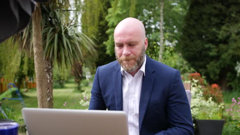 a man on conference call in garden on laptop