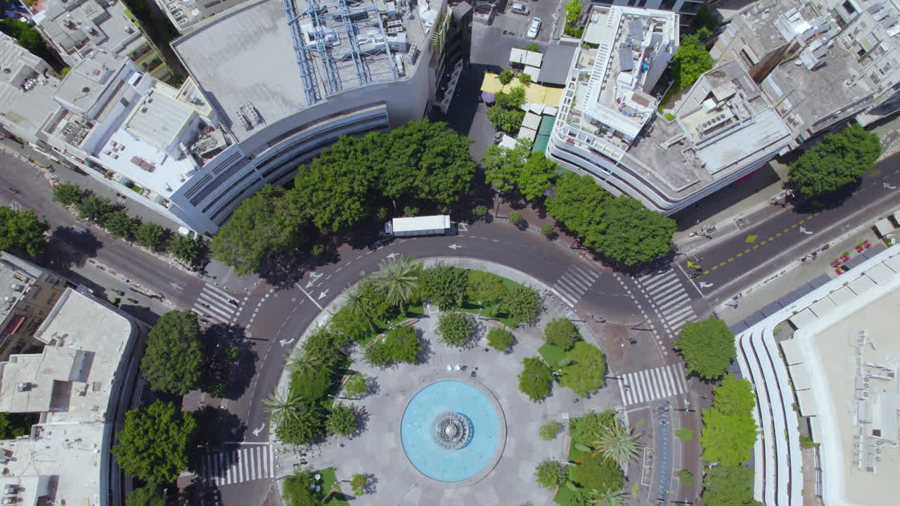Dizengoff Square to the Tel Aviv beaches on a hot summer day as people sit and enjoy the shade of the square's trees - top down to tilt up shot