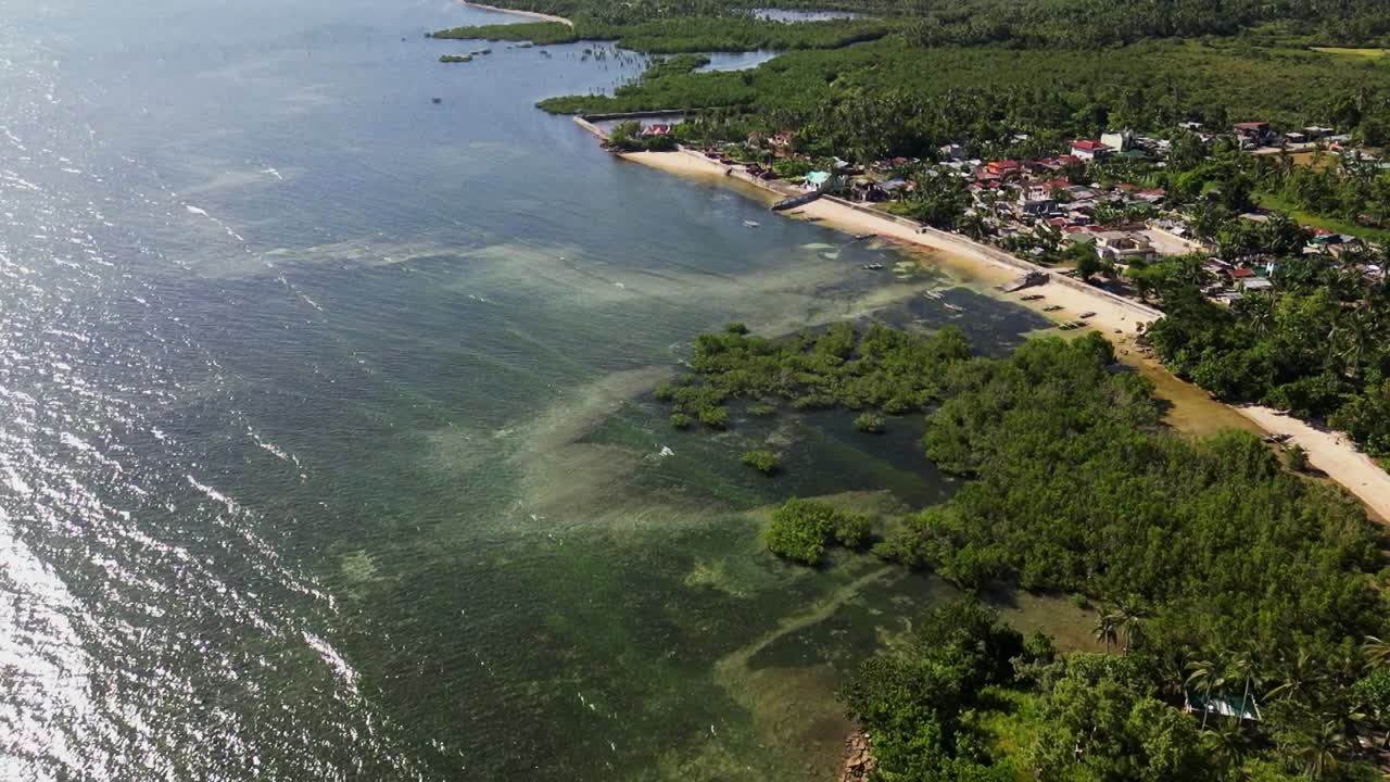 Scenic overhead drone shot of the oceanfront rural village town Yocti at lush, tropical island Catanduanes, Philippines during daytime.