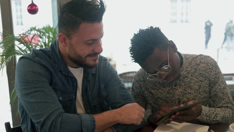 Cheerful-friends-using-smartphone-and-talking-in-coffee-shop