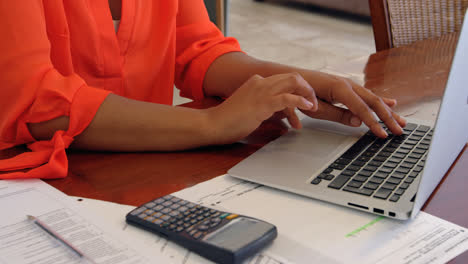sección media de una mujer trabajando en una computadora portátil en un escritorio en casa 4k