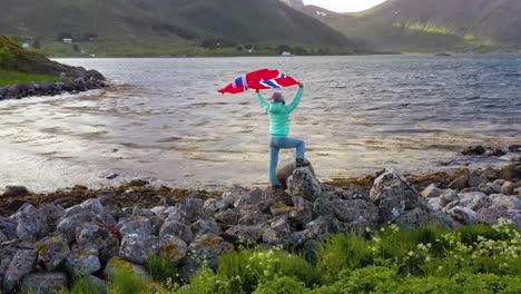 woman with a waving flag of norway on the background of nature