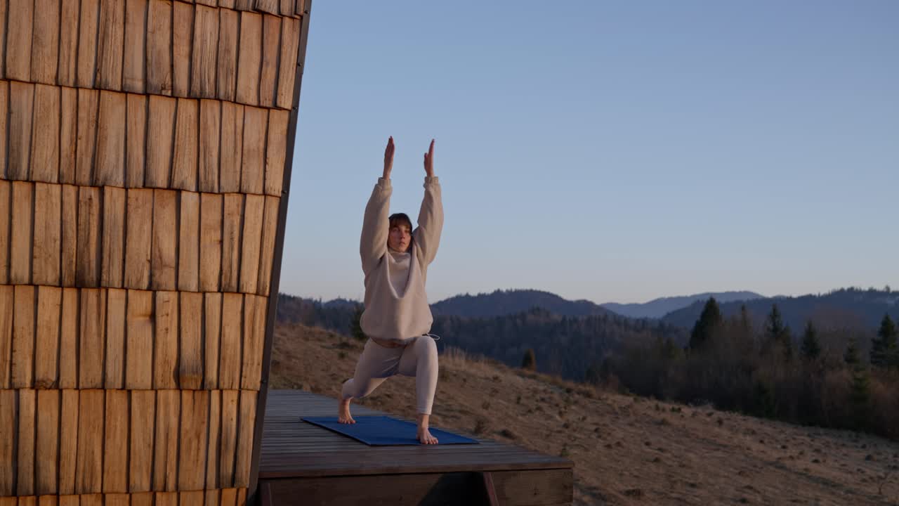 Woman doing yoga on a platform in the mountains