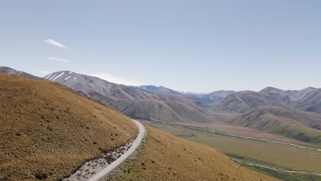 curved road on dry, bushy mountainside in southern alps of new zealand