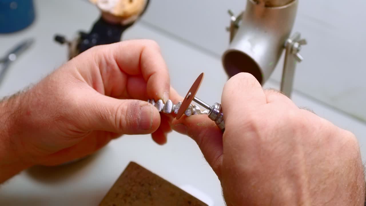 un técnico dental pulida dentaduras metálicas en su taller