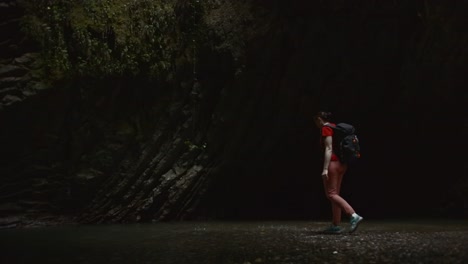 woman hiking through a dark canyon