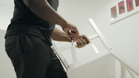 black man hands keeping chair at kitchen. closeup hands repairing wooden chair.