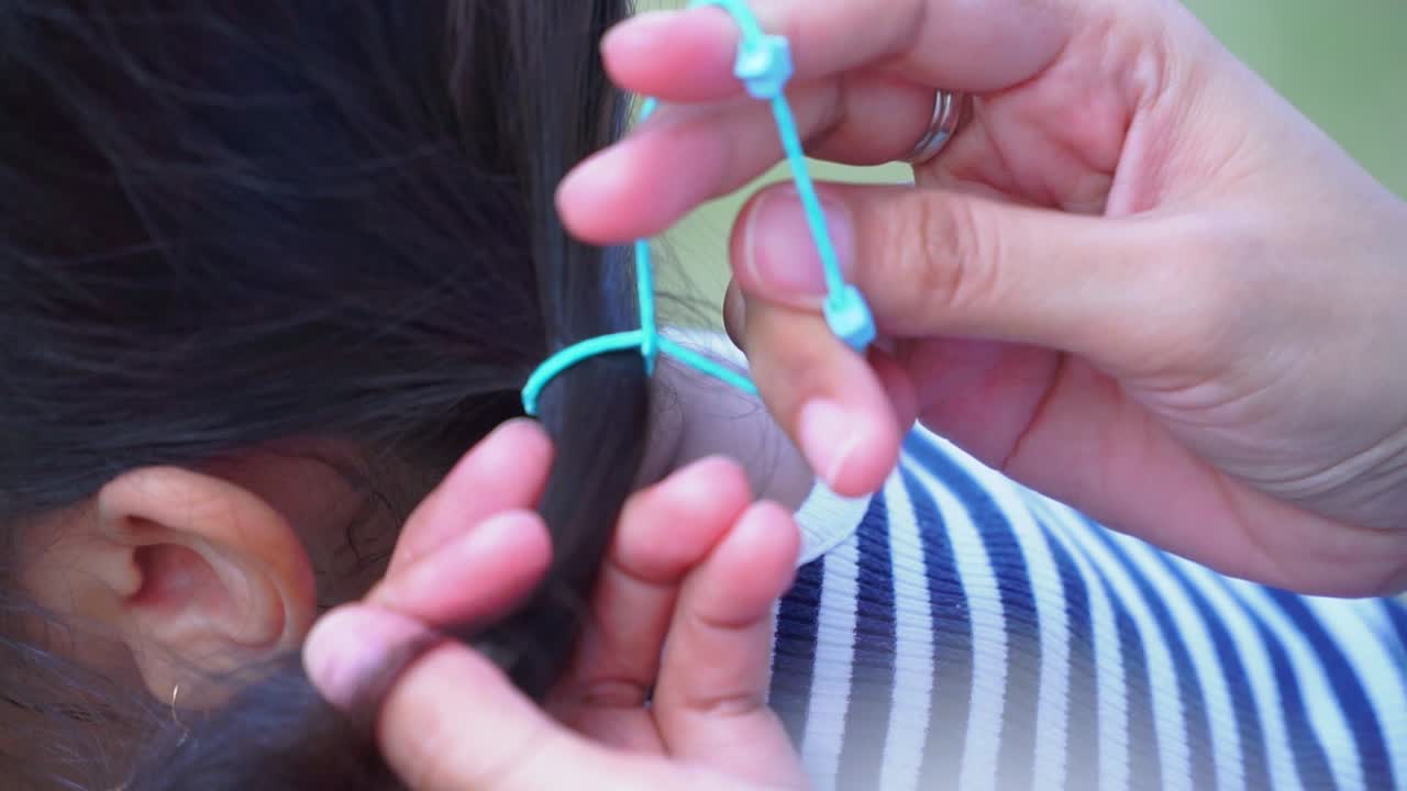 Hand of mom is making ponytail on daughter black hair - Close up shot