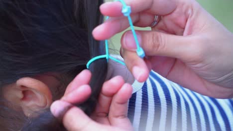 Hand-of-mom-is-making-ponytail-on-daughter-black-hair---Close-up-shot