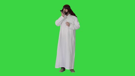 arabian businessman recording voice message or using voice digital helper on a green screen, chroma key