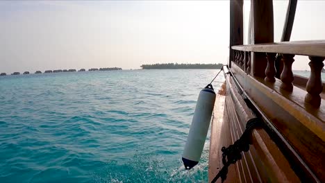 Low-side-view-of-Wooden-boat-in-ocean-sailing-towards-island