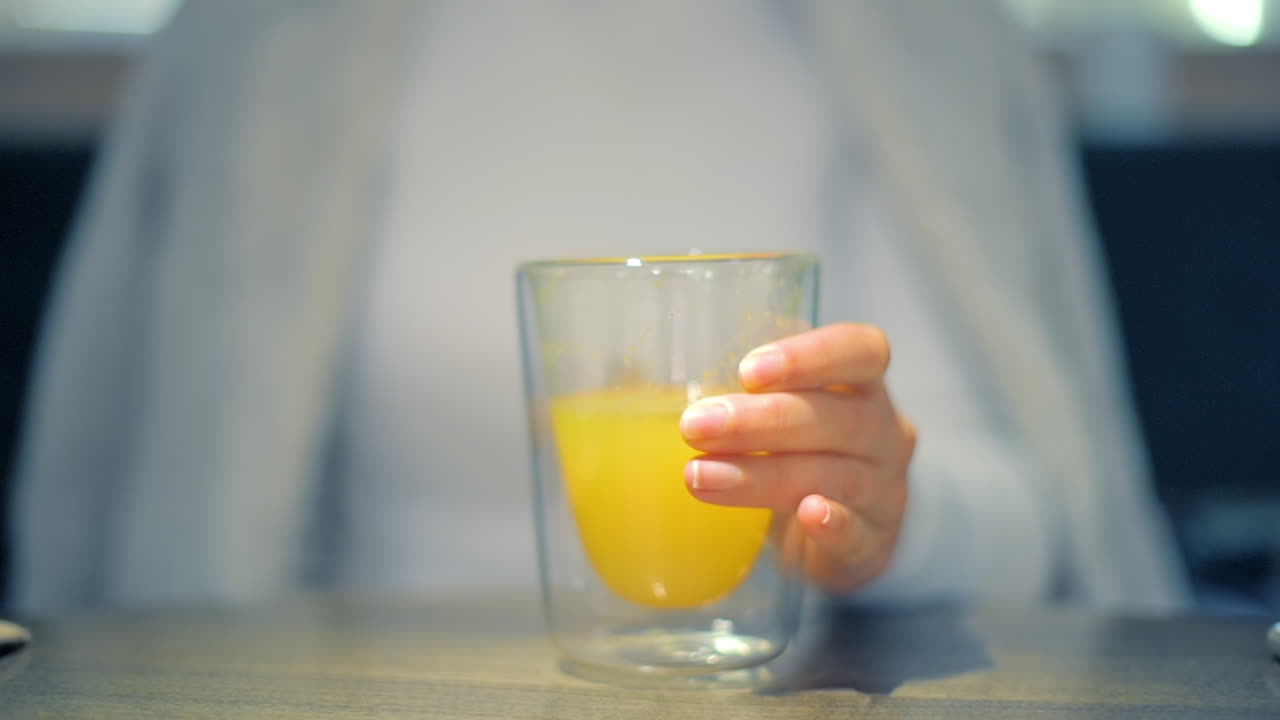 Mujer bebiendo un refresco de naranja en un vaso doble