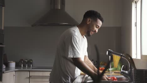 Ethnic-man-washing-bell-pepper-during-cooking-preparation