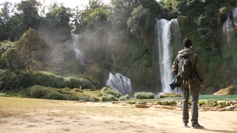 Traveller-With-Backpack-Standing-And-Admiring-The-Water-Flowing-At-Ban-Gioc-Detian-Falls-In-Vietnam