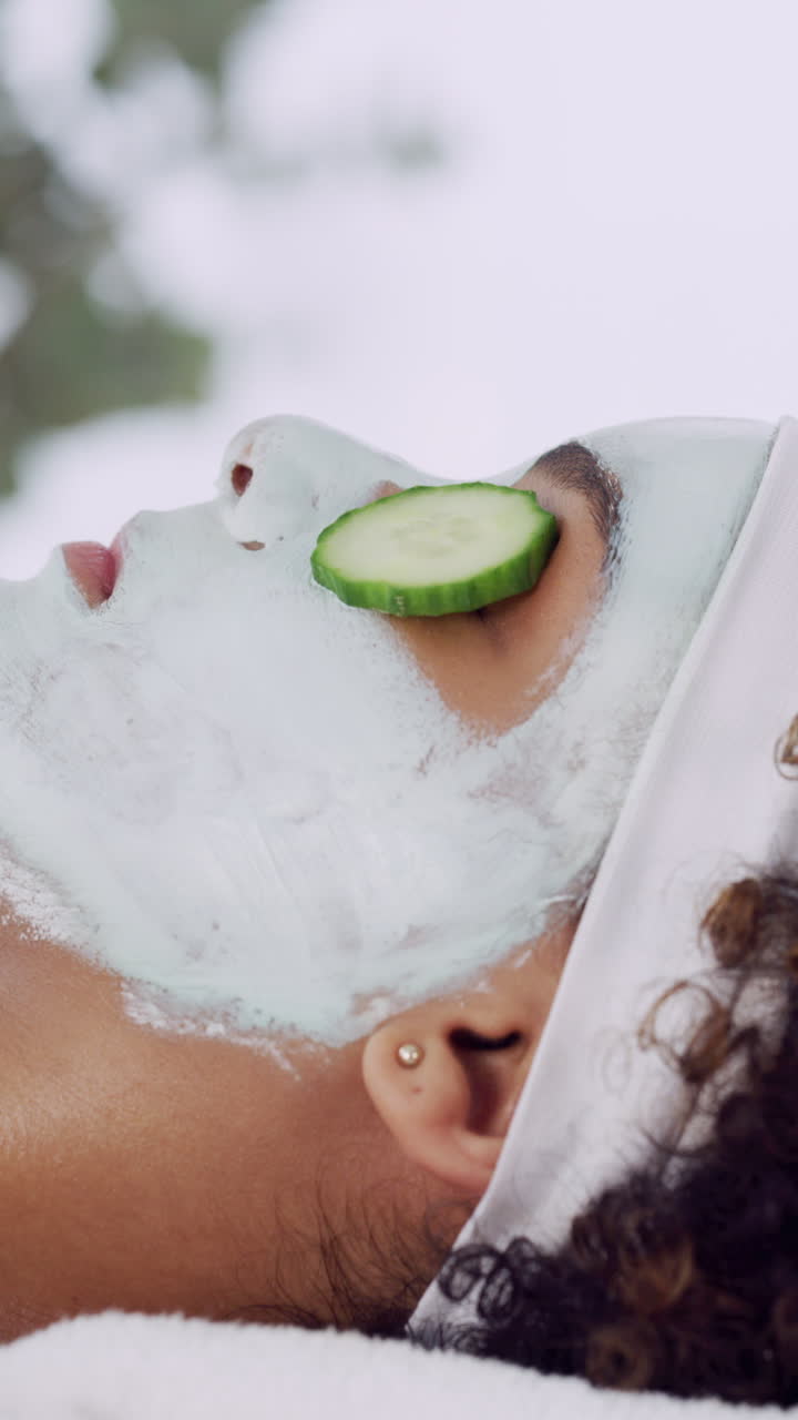 Jovem Mulher com Máscara Facial e Rodela de Pepino Relaxando em um Spa
