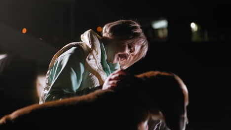 sports lady seated with sport pet during nighttime training session, gently communicating and bonding with her loyal dog while illuminated softly against dark background, expressing affection