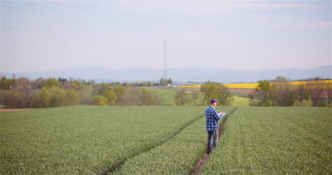 agronomist examining crops and writing notes in clipboard on field 1