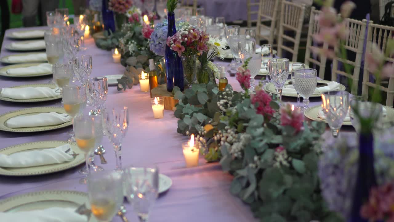 Lungo tavolo da banchetto con tovaglia viola e bicchieri a un ricevimento di matrimonio all'aperto