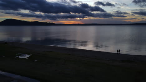 Paar-Silhouette-Gegen-Einen-Strand-In-Der-Abenddämmerung-Mit-Bergen-Im-Rücken