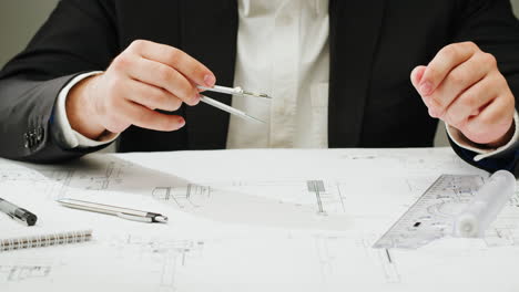 hands of an engineer or architect working on technical drawings with tools