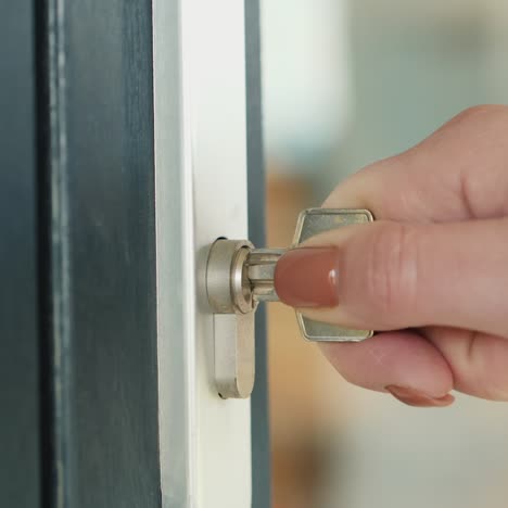 the woman slowly inserts the key into the keyhole of the front door