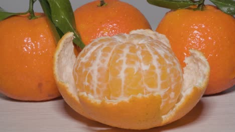 close up shot rotating around a kitchen table to reveal a half peeled ripe mandarin orange, a sweet tasting citrus fruit which is easy to peel for a healthy organic snack