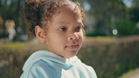 adorable dark skin child portrait standing with mother at sunny park.