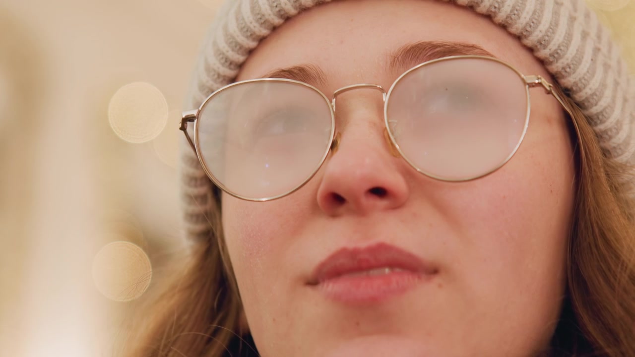 Intieme scène met zachte gloed en peinzende stemming. Jonge vrouw met emotionele blik te midden van zachte bokeh-lichten. Close-up die kwetsbare vrouw met tranende ogen en warme sfeerverlichting vastlegt.