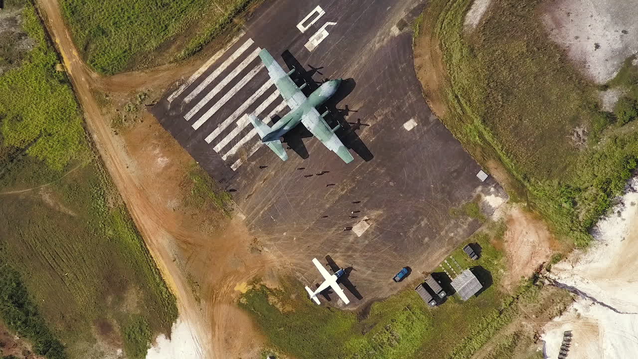 Top view aerial shot as people approaching a C-130 Hercules airplane on a runway