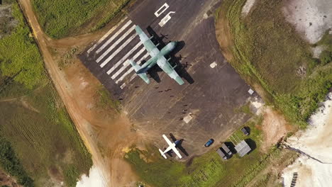 top view aerial shot as people approaching a c-130 hercules airplane on a runway
