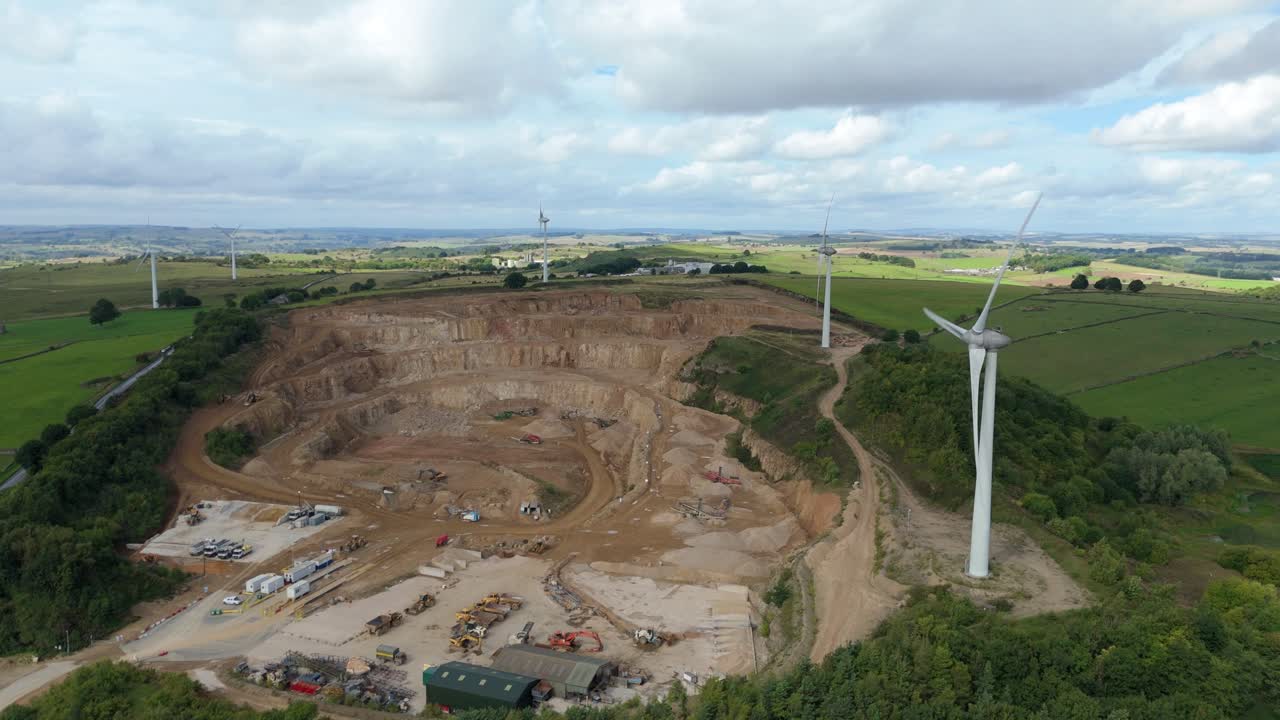 Vista aerea da drone di turbine per energia rinnovabile con fabbriche e cava in verdi colline rurali Derbyshire Dales, Regno Unito