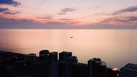 Aerial-view-of-commercial-aircraft-landing-over-Black-sea-and-touching-down-the-airport-runway-at-sunset