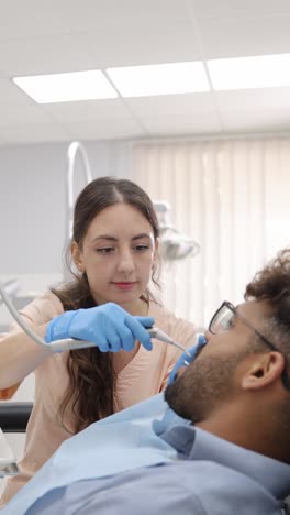 a patient receives professional oral health care from a dental team. during a routine visit, the dentist and assistant work on a tooth, illustrating a standard procedure for maintaining healthy teeth.