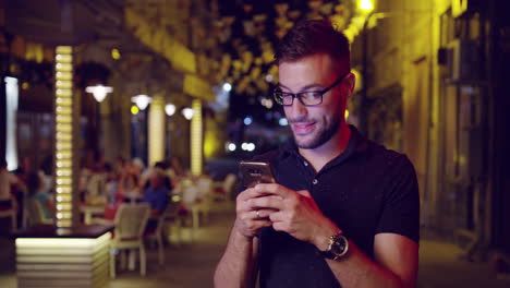 hombre sonriendo mientras usa el teléfono inteligente en