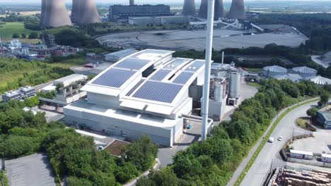 clean solar rooftop installation on modern office building aerial view with coal power station in background push in tilt down