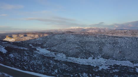 En-Un-Día-Soleado,-Un-Dron-Capturó-Esta-Fotografía-Cenital-De-Una-Carretera-Que-Atraviesa-Montañas-Cubiertas-De-Nieve,-Cubierta-De-Escasa-Vegetación-Y-Cubierta-Por-Nubes