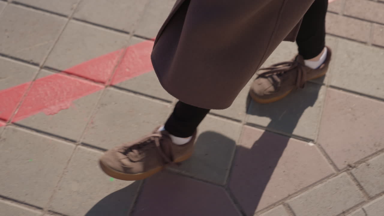 Scarpe marroni attraversano con cautela un confine rosso brillante. Calzature attraversano attentamente una vistosa linea rossa in un ambiente stradale. Scarpe marroni stanno delicatamente attraversando una vivida linea di confine rossa in un contesto urbano.
