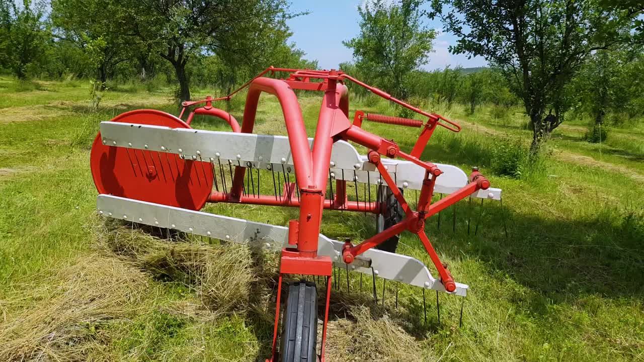 máquina henificadora de heno en el trabajo haciendo heno en el campo en un día soleado - cerrar